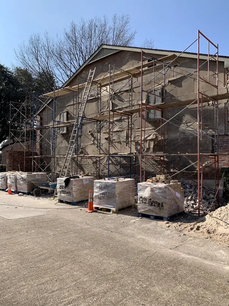 Two-story home with scaffolding and pallets of brick for veneer work
