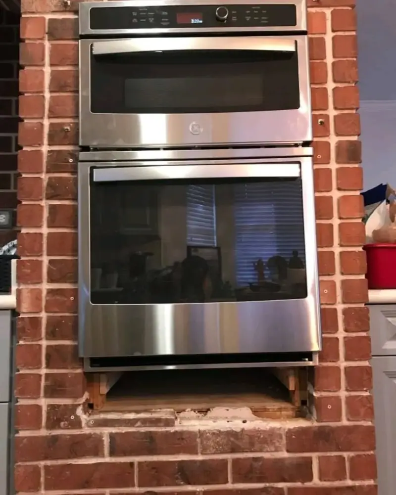 Stainless built-in wall ovens framed in red brick