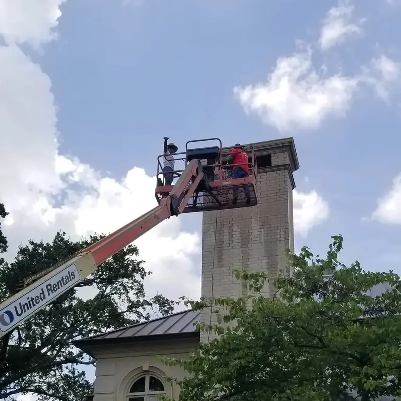Crew working on a tall chimney from an aerial lift