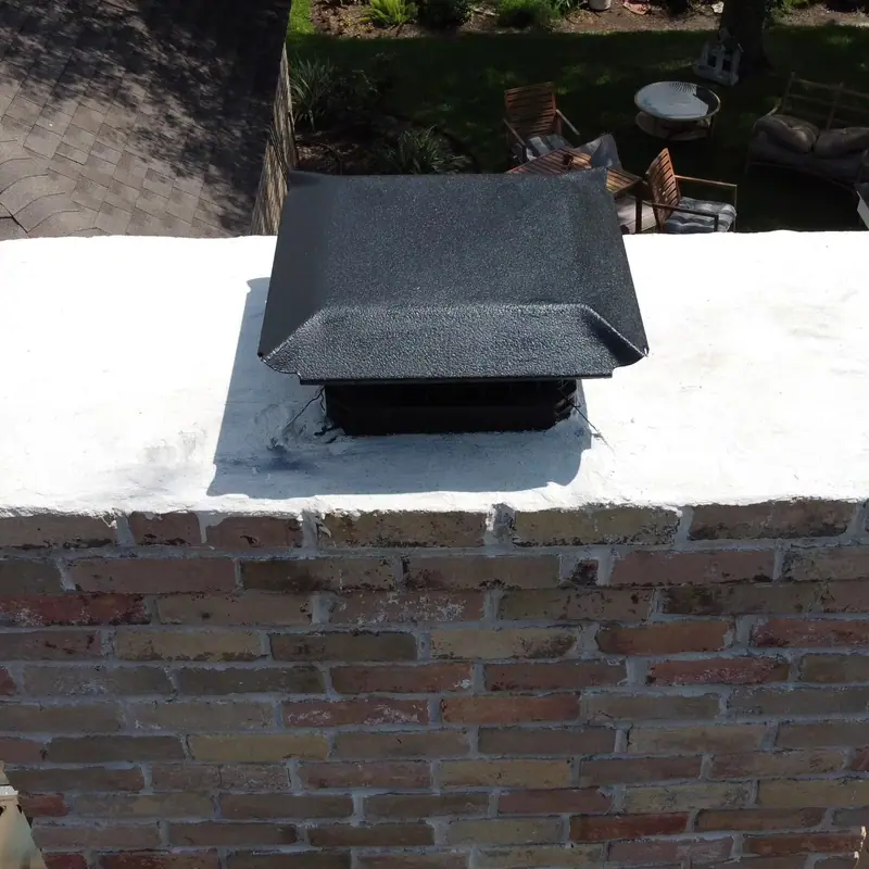 Smooth new chimney crown with a black metal cap