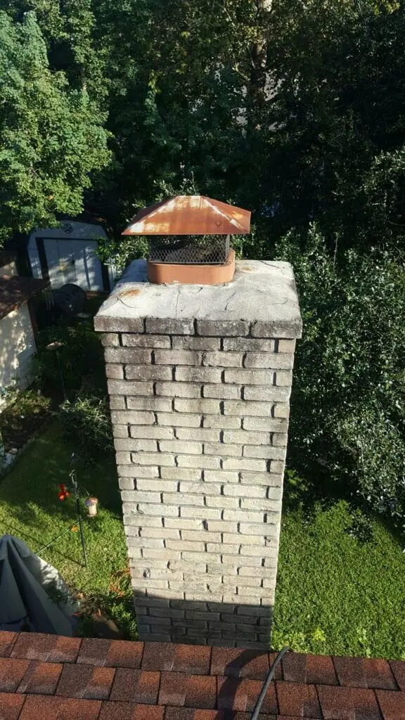 Painted brick chimney with a copper cap, before repair