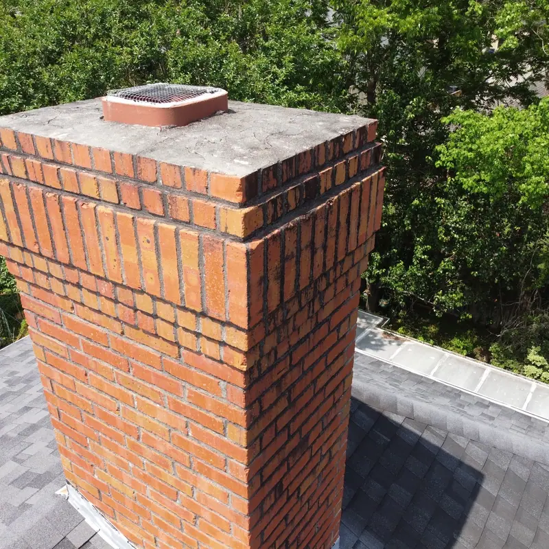 Restored red brick chimney top with a chimney cap