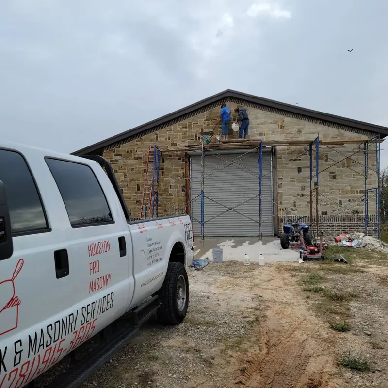 Houston Pro Masonry truck at a commercial building with scaffolding on the brick facade