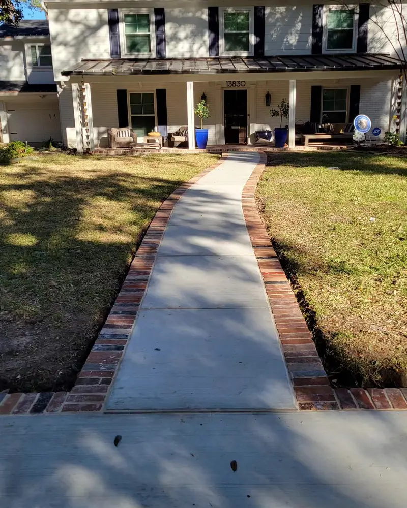 New concrete front walkway with a red brick border leading to a two-story home