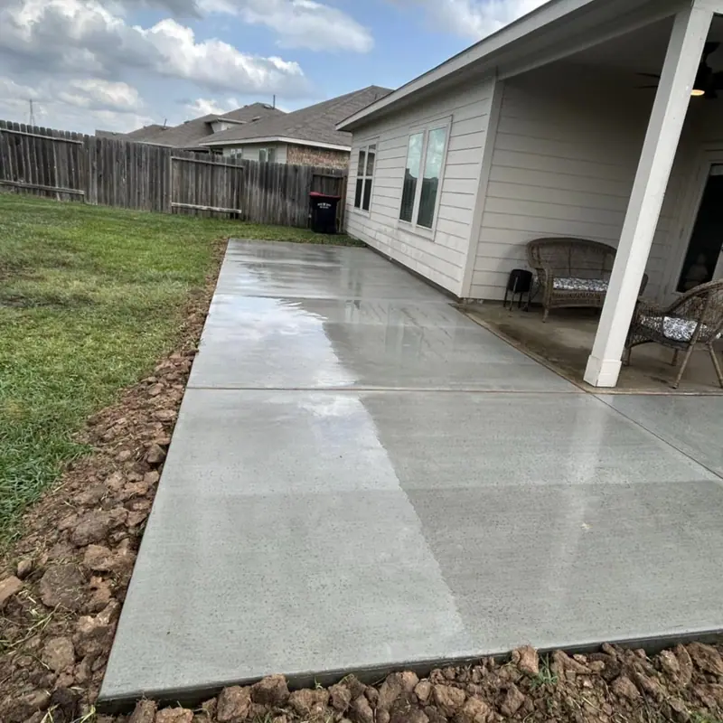 New concrete walkway and patio along the side of a house