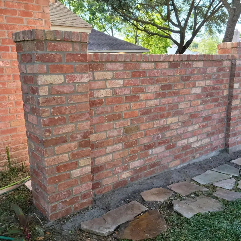 Rebuilt courtyard brick wall with a flagstone path in front