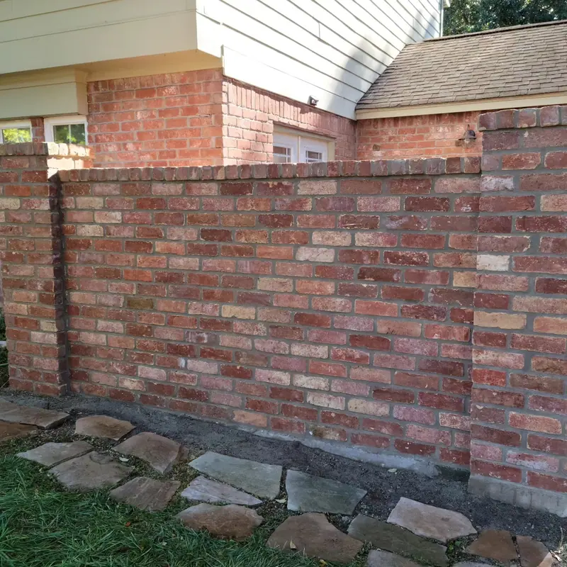 Rebuilt brick courtyard wall beside a house