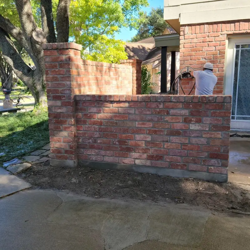 Mason finishing a rebuilt courtyard brick wall