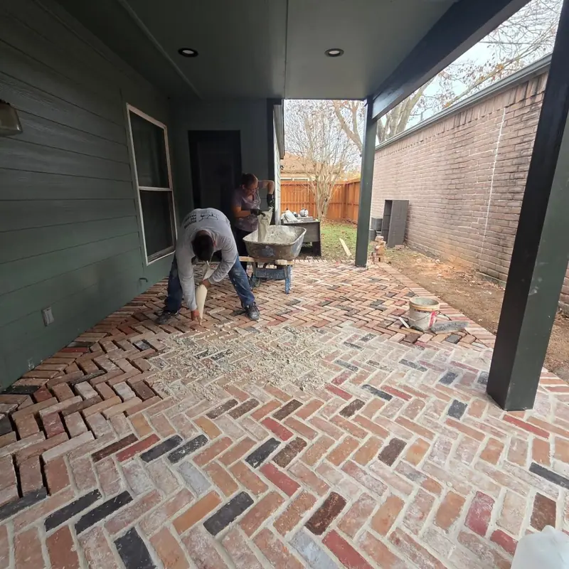 Crew member laying herringbone brick pavers on a covered porch