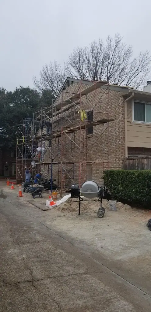 Scaffolding and mortar mixer set up beside a two-story brick home