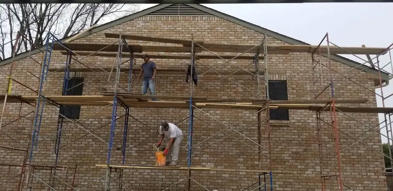 Crew working from scaffolding on a two-story brick wall
