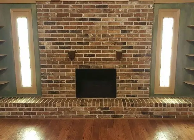 Restored interior brick fireplace with a raised hearth and lighted side panels