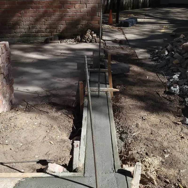 Trench dug and formed for a new footing beside a brick wall