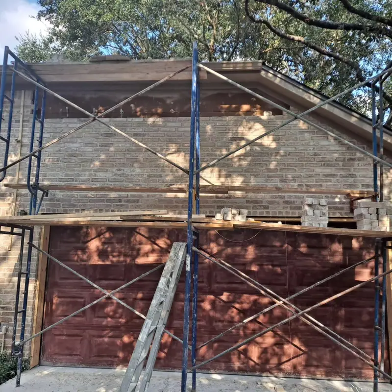 Brick being rebuilt above a garage door from scaffolding