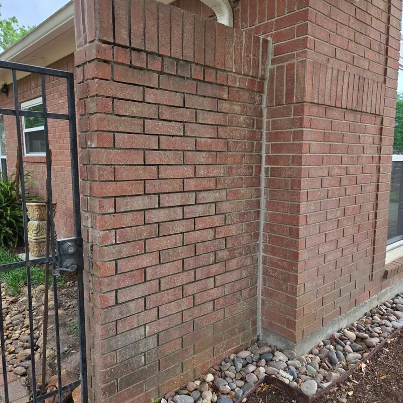 Brick column beside an iron gate pulling away from the adjoining wall