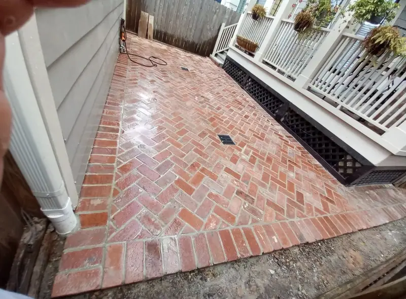 Herringbone brick patio with a brick border beside a white railing