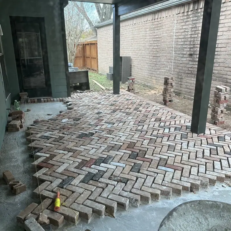 Herringbone brick porch floor partway through installation under a covered porch