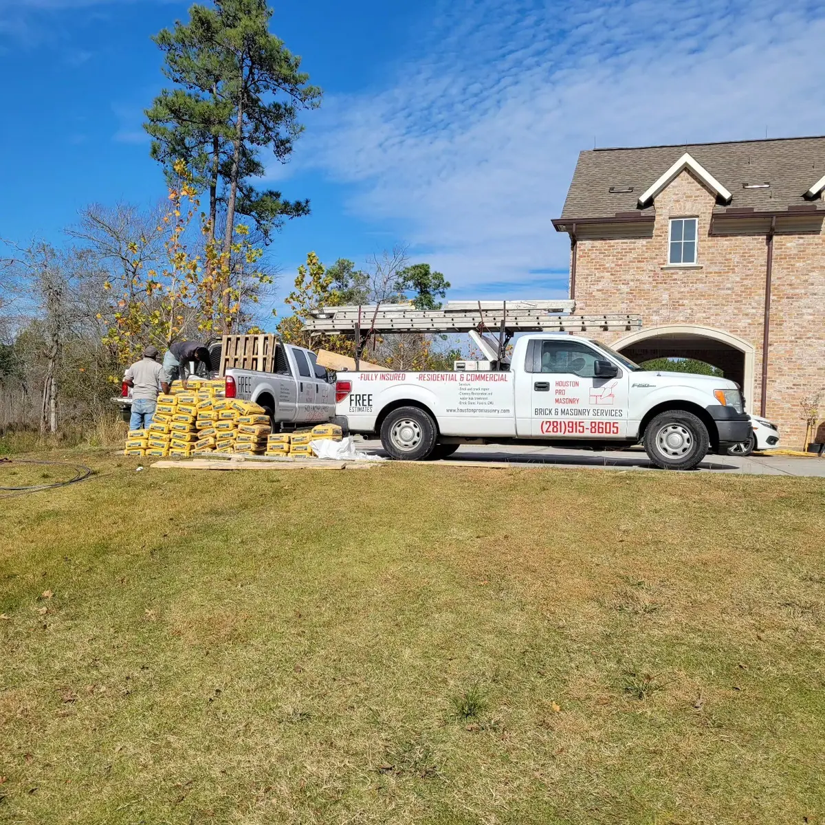 Houston Pro Masonry truck beside pallets of brick at a two-story brick home