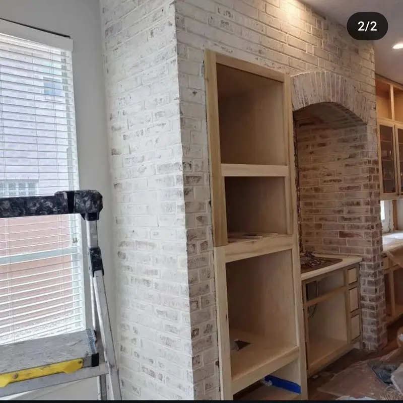 Interior brick wall with a light whitewash finish around an arched niche and built-in shelves