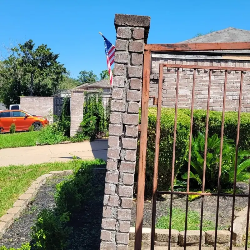 Brick column beside an iron gate leaning out of plumb