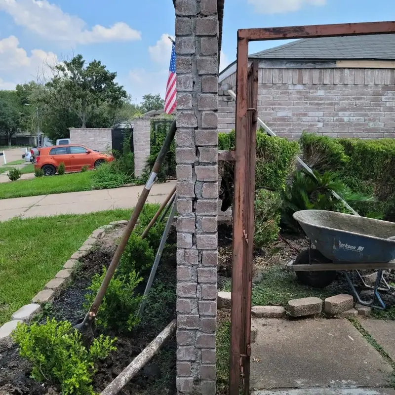 The same brick gate column during repair, with tools at its base