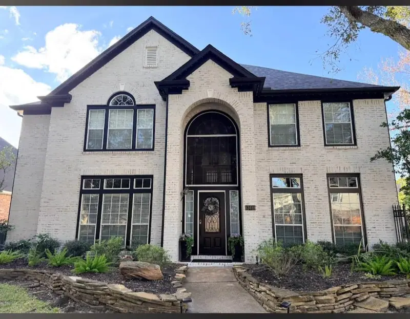 Two-story home with light brick and stone and an arched entry