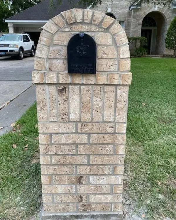Brick mailbox with an arched top and black mail door