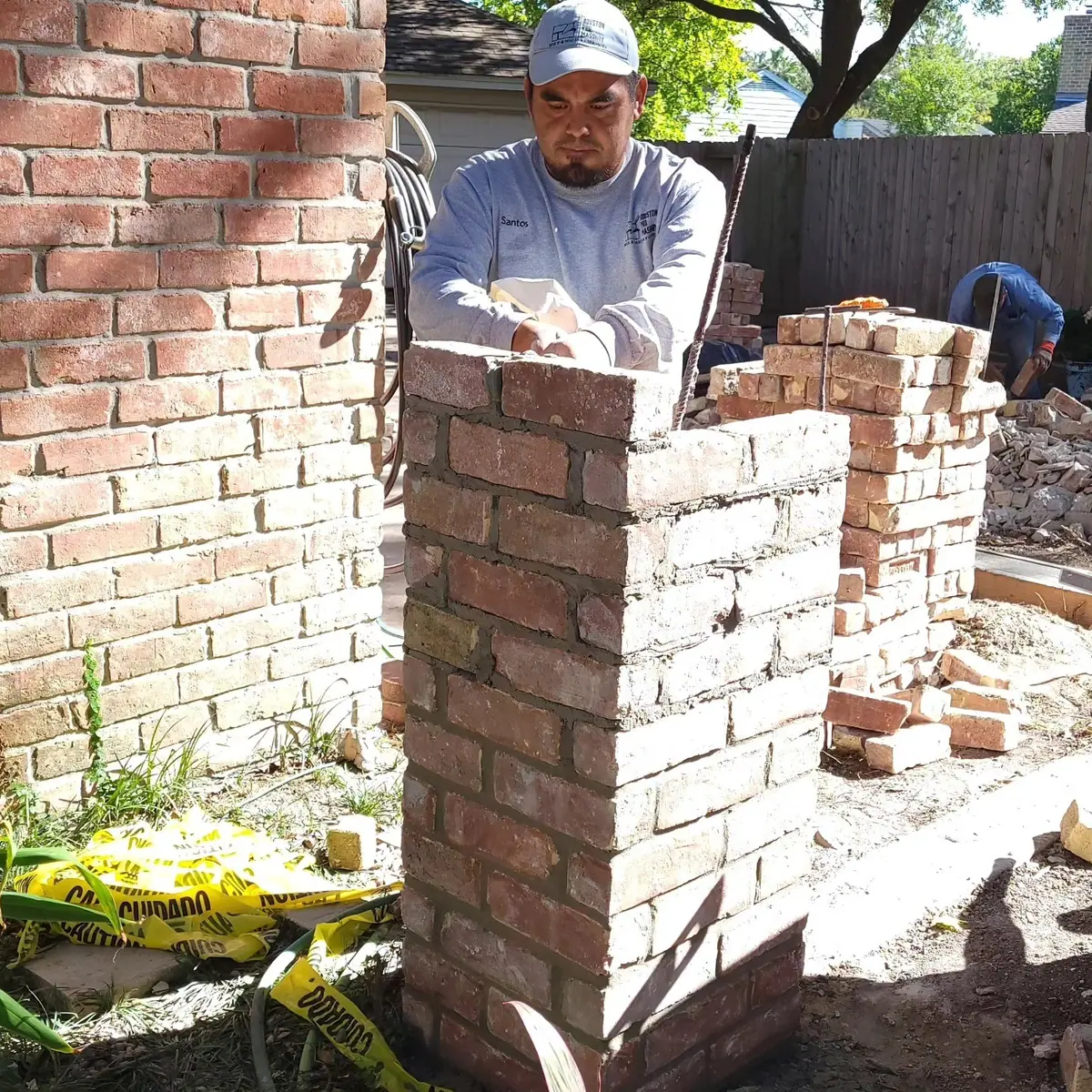 Houston Pro Masonry mason setting brick on a column during a brick privacy wall rebuild