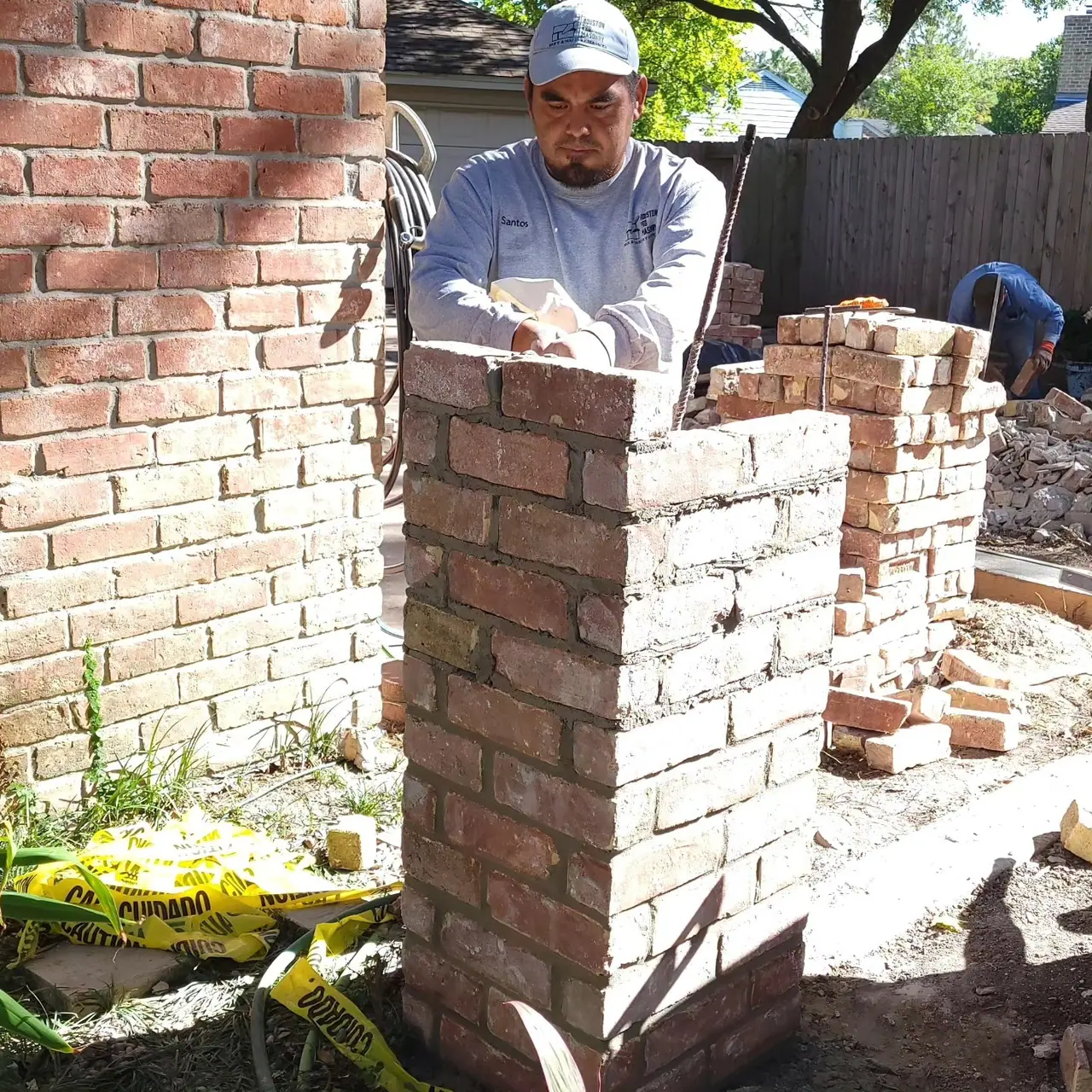 Houston Pro Masonry mason setting brick on a column during a brick privacy wall rebuild