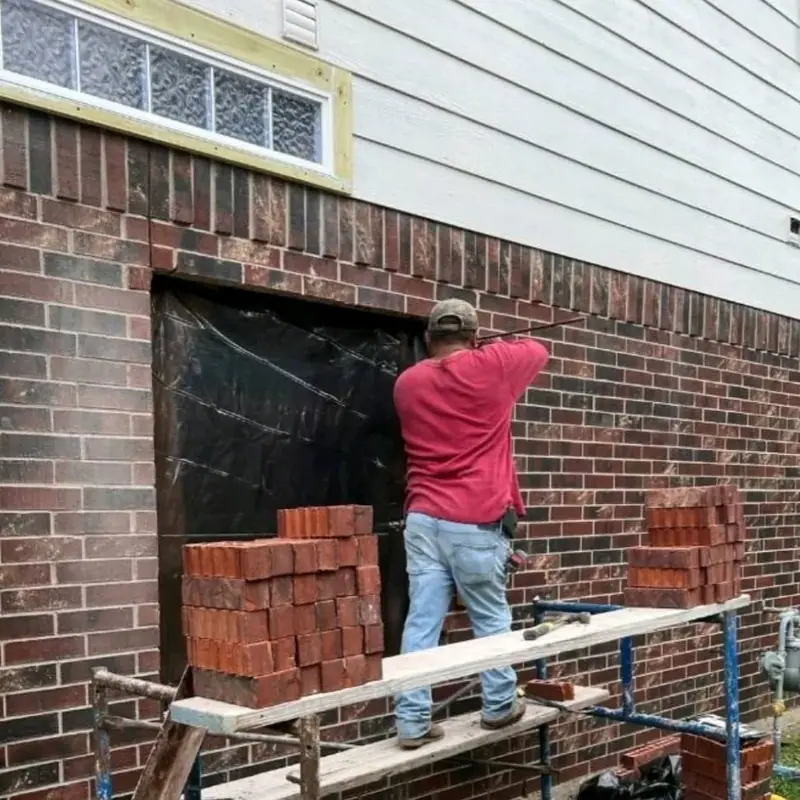 Mason on a scaffold laying brick around a window opening