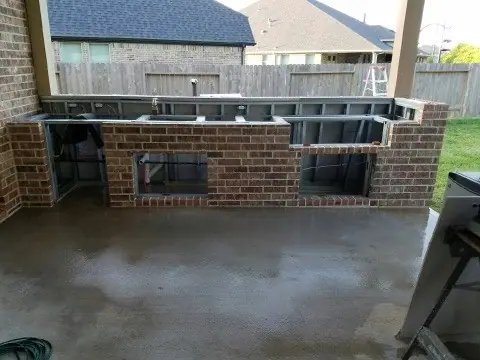 Outdoor kitchen island with a brick base under construction on a patio