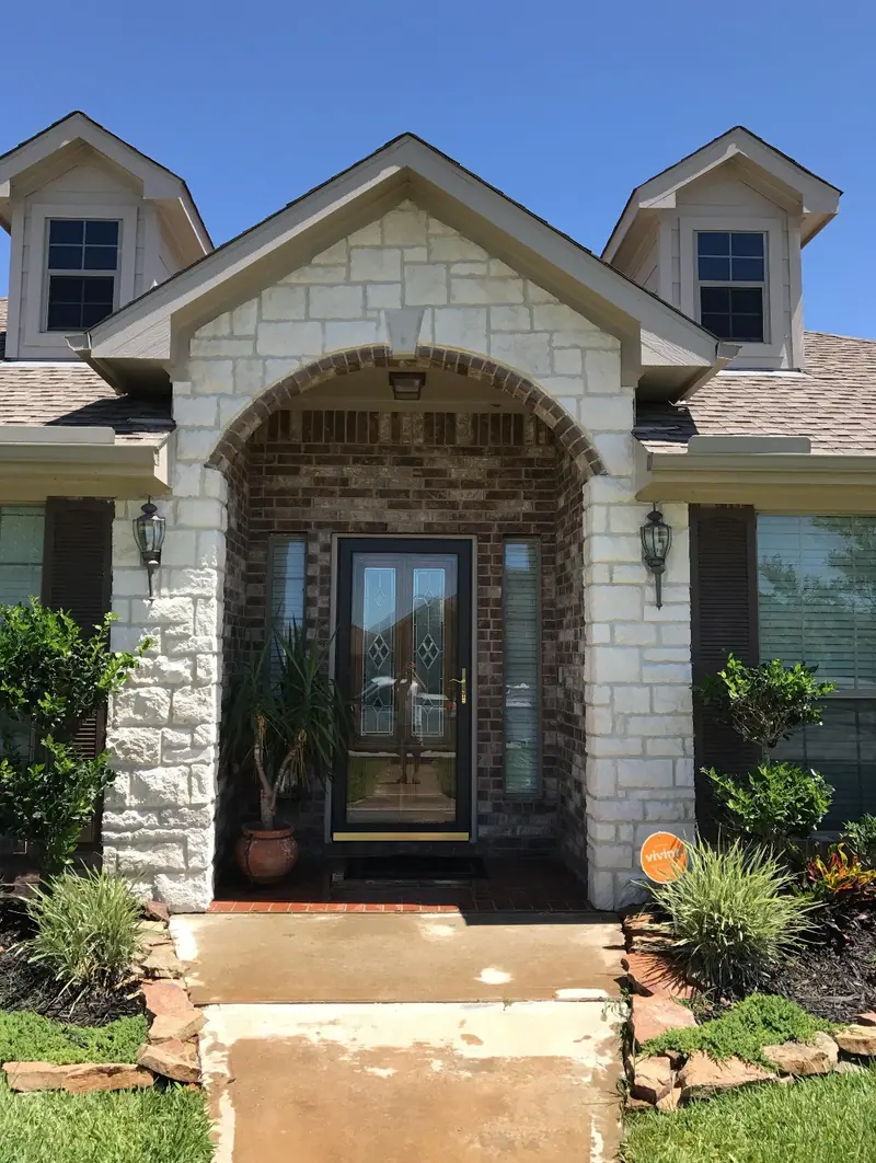 Front entry faced in light stone with an arched opening