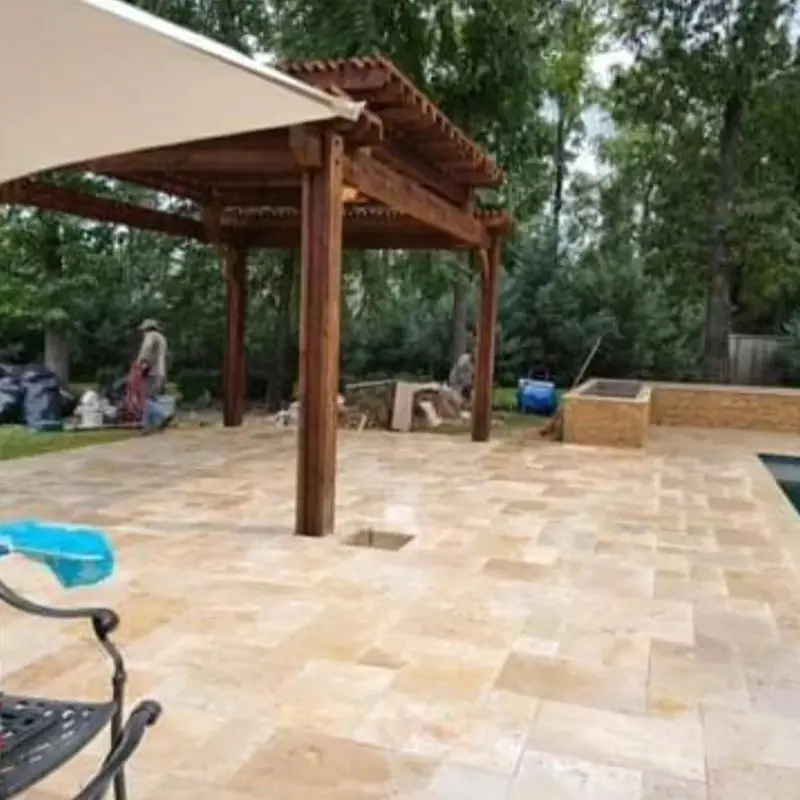 Stone paver patio under a wooden pergola beside a pool