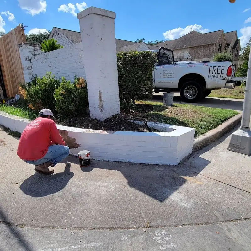 Crew member working at the base of a painted brick corner wall
