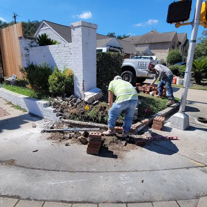 Crew rebuilding a damaged painted brick wall at a street corner